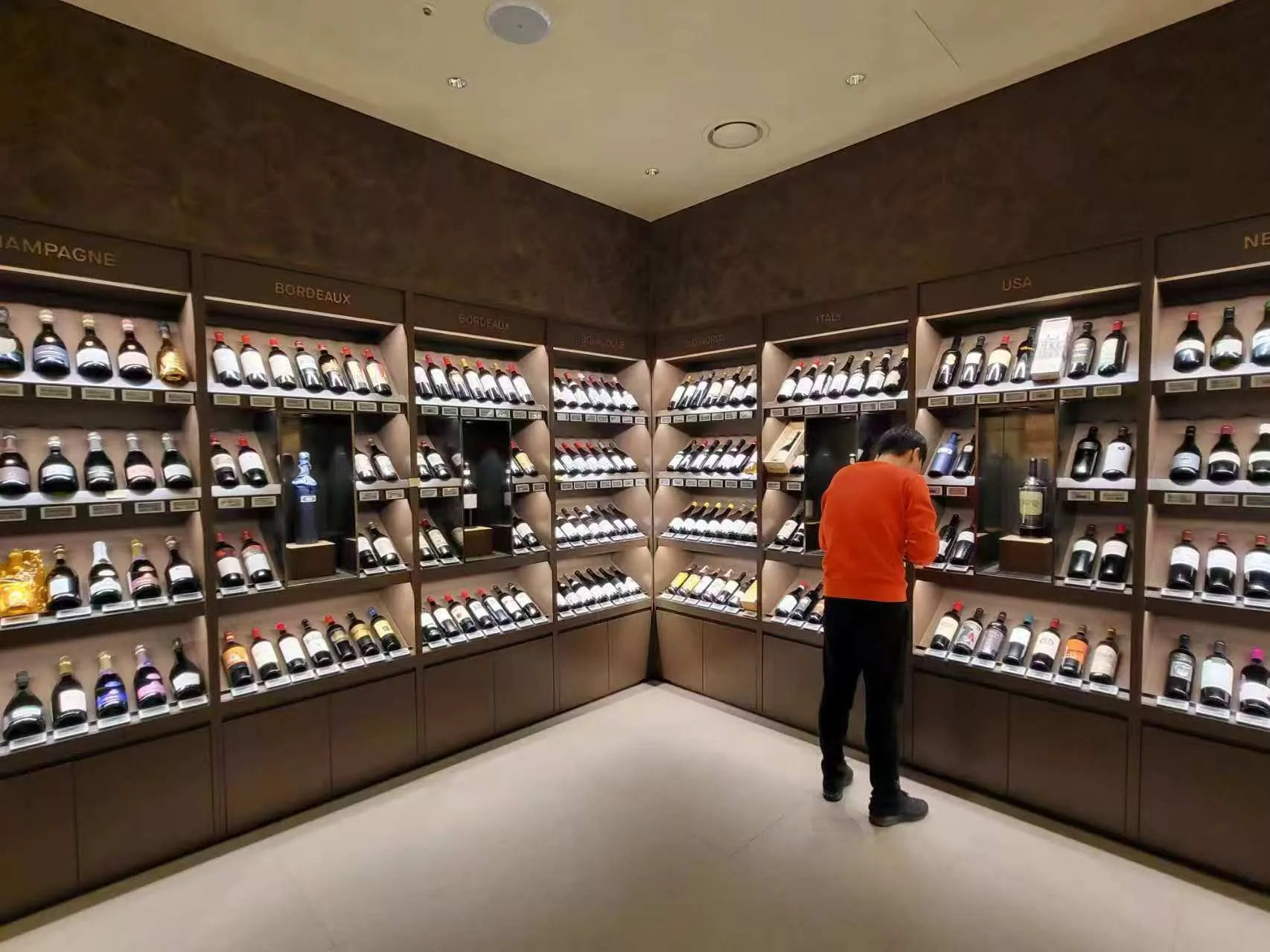 Wine shelving with integrated linear lighting inside Lotte Duty Free Singapore.